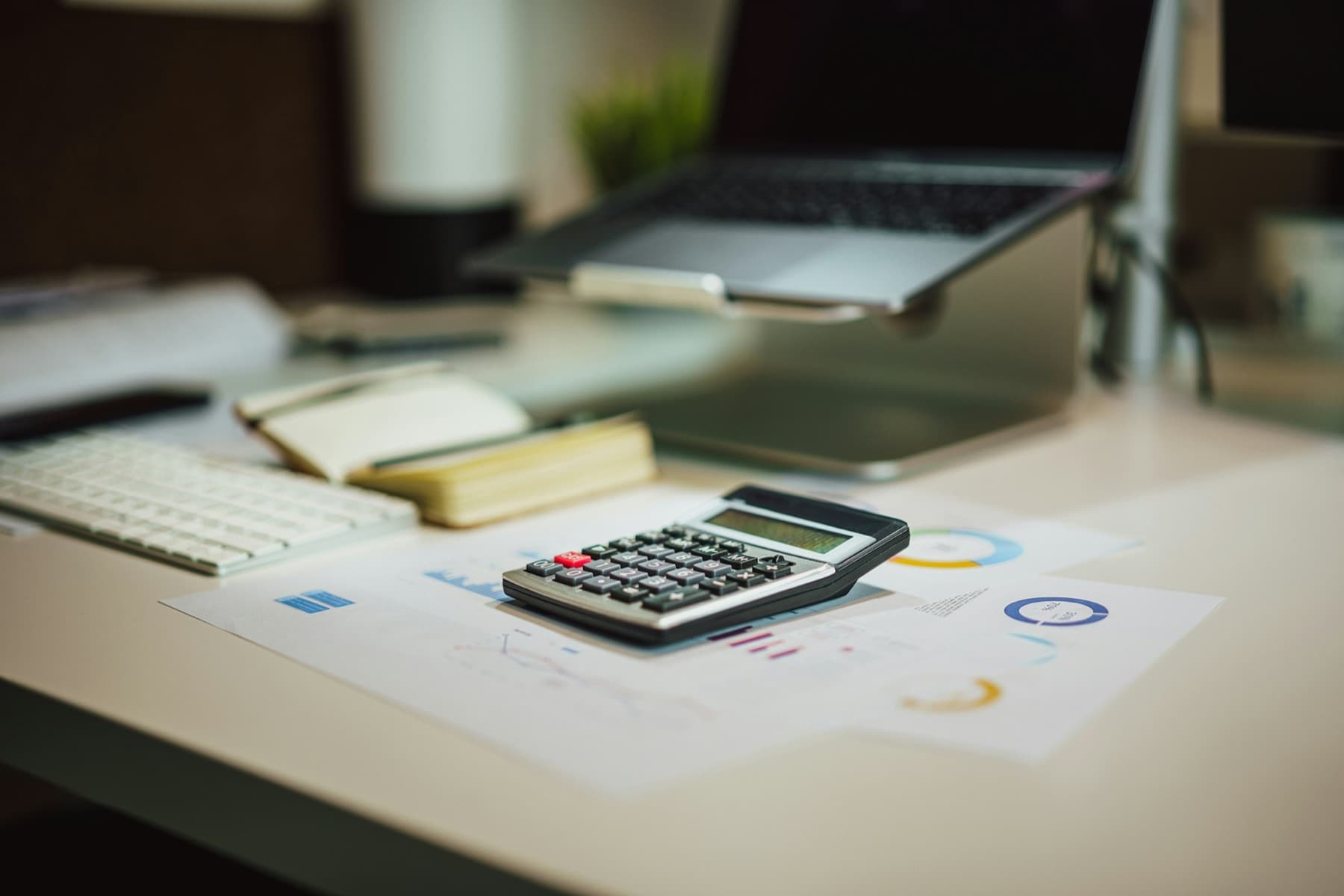 A calculator next to a laptop on a work desk