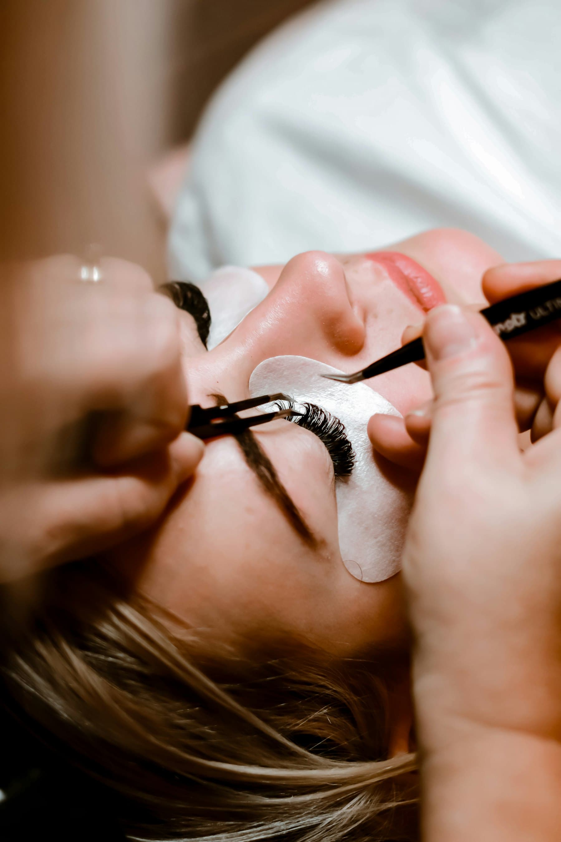 A lash artist applying lashes with fine tweezers