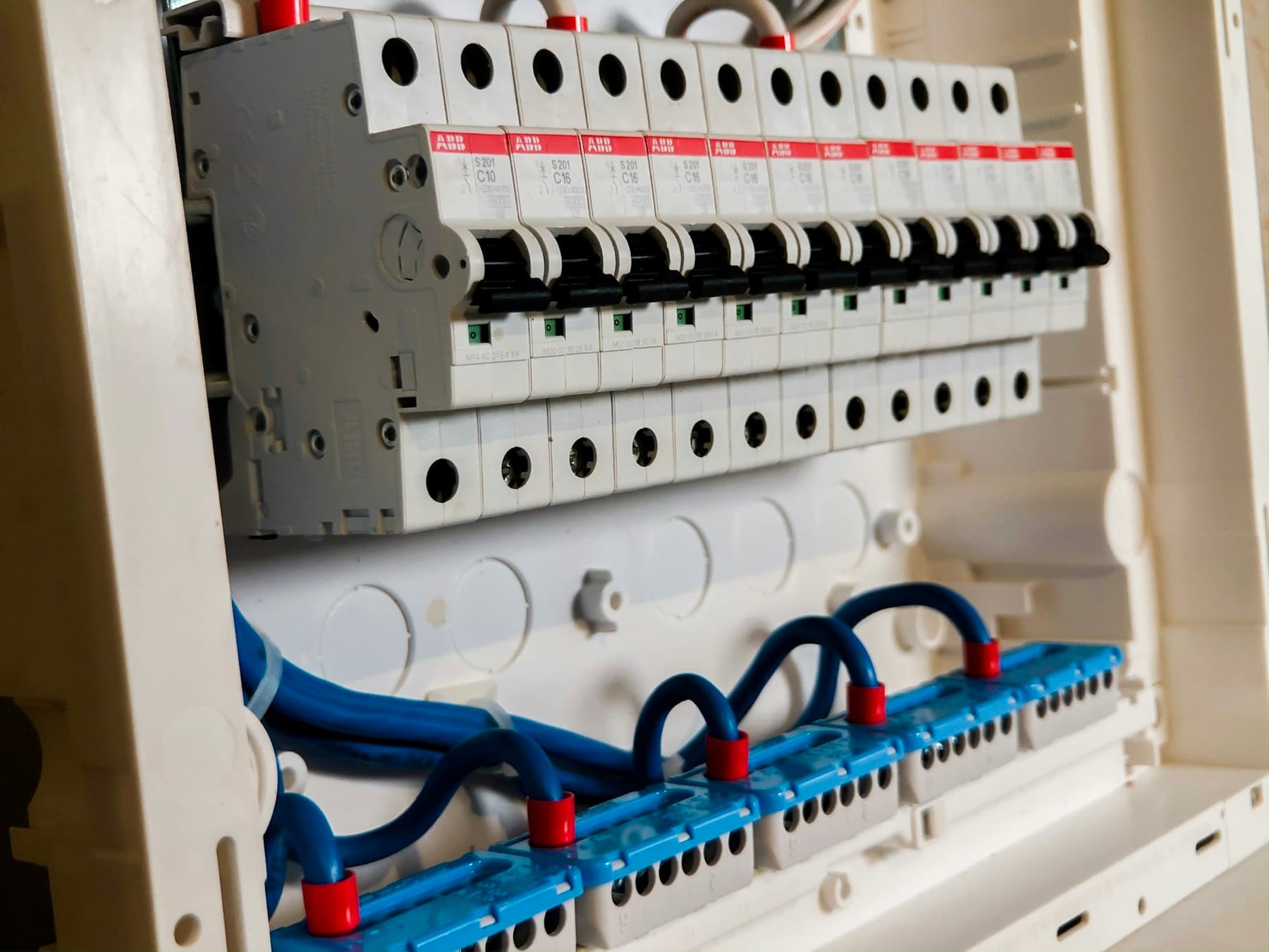 Opened switchboard with a row of new circuit breakers and neatly looped blue wiring